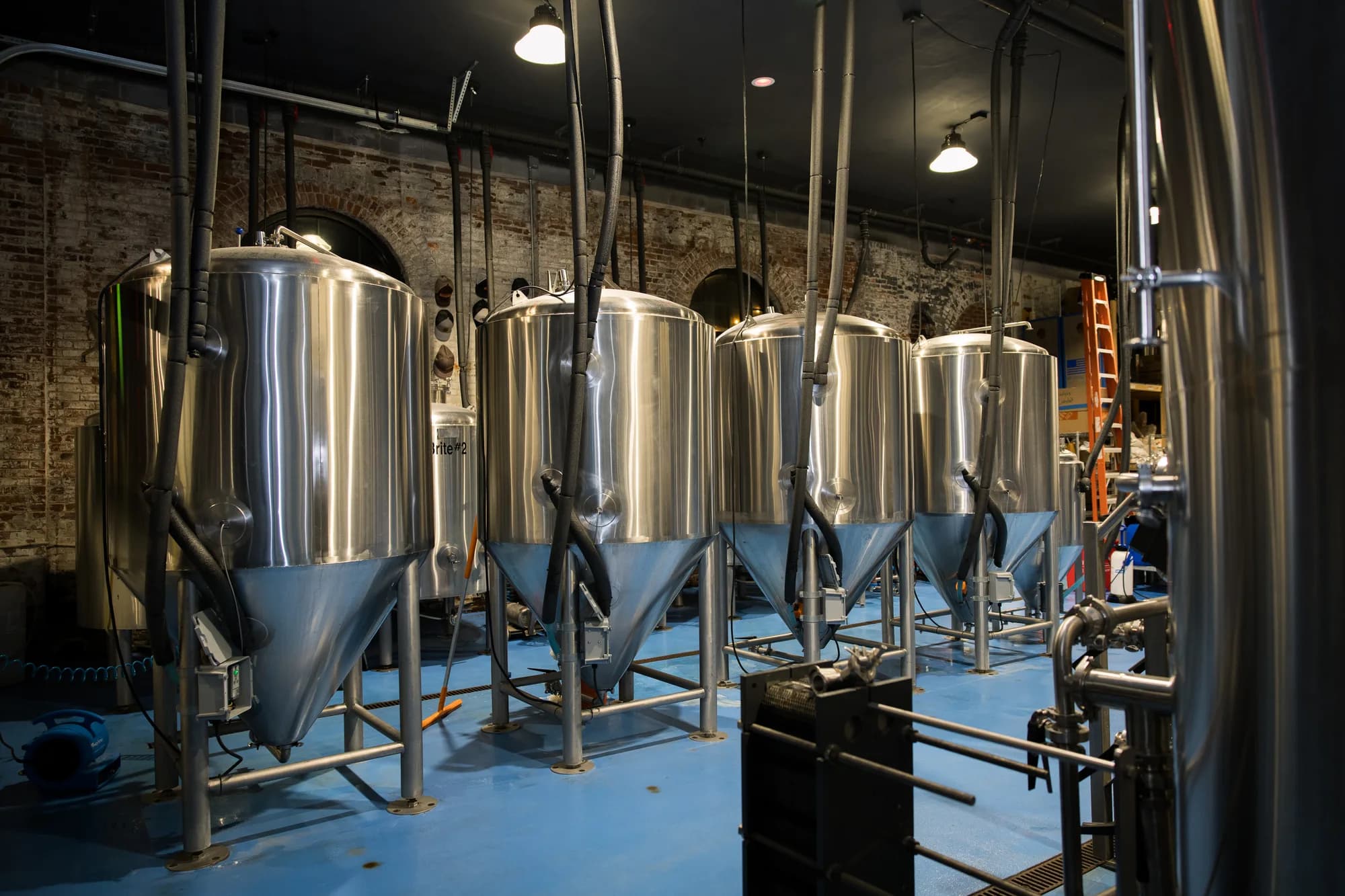 Stainless fermentors under the brick arches of the tank room
